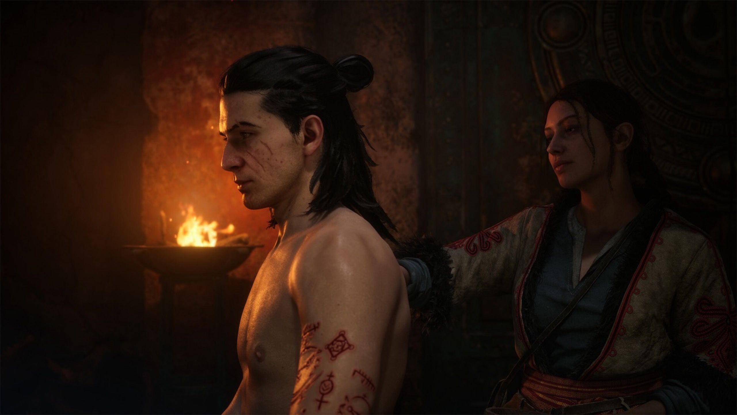 Coen, his injured arm in a sling, sitting by a campfire with a female companion.